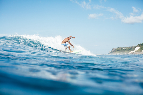 side view of handsome young man surfing on sunny day