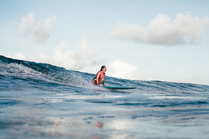 young sportswoman in process of standing on surfboard while surfing
