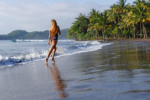 rear view of girl running on tropical beach near ocean