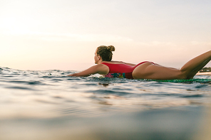 sportswoman in swimming suit surfing alone in ocean