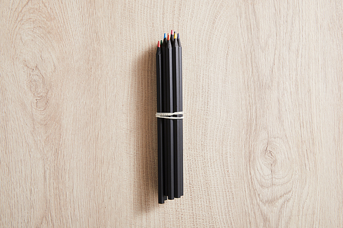 top view of black colored pencils on wooden beige surface