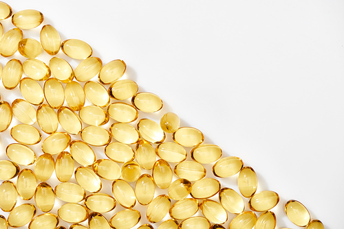 flat lay with golden fish oil capsules on white background