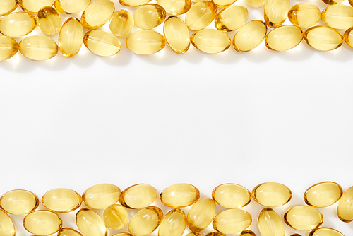 top view of golden fish oil capsules arranged in frame on white background