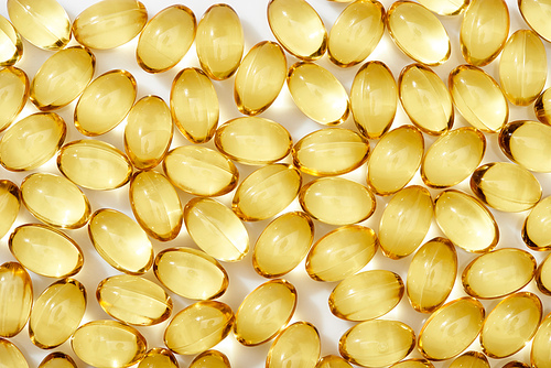 top view of golden fish oil capsules on white background