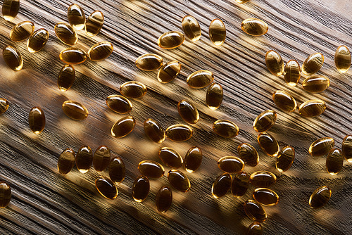 shiny golden fish oil capsules scattered on wooden table