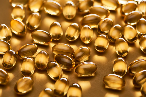 shiny fish oil capsules on golden background