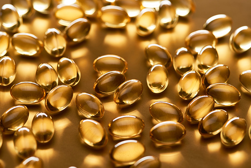 shiny fish oil capsules on golden background