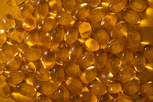 top view of golden shiny fish oil capsules in dark