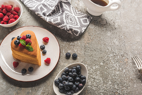 top view of heart shaped pancakes with berries on grey concrete surface with maple syrup and napkin