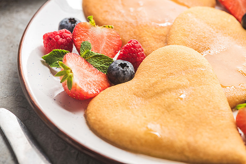 close up view of delicious heart shaped pancakes with berries on plate