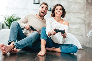 low angle view of happy man and woman playing video game at home