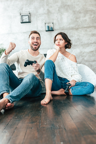 low angle view of upset woman looking at happy man gesturing while playing video game