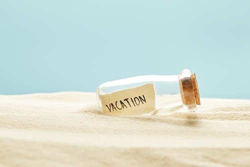 glass bottle with vacation lettering on paper in summertime isolated on blue