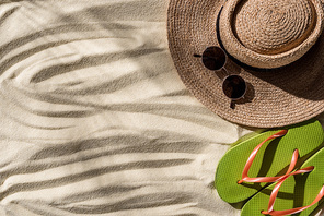 top view of straw hat, flip flops and sunglasses on wavy sand with copy space