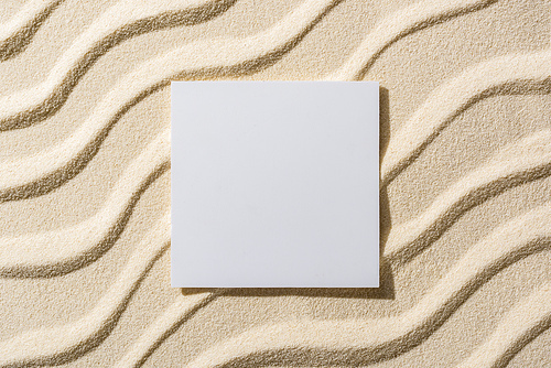 top view of sandy background with smooth waves and blank card
