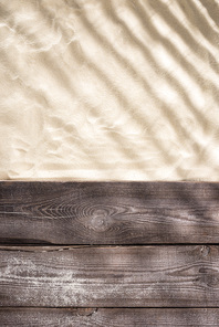 top view of sand with shadows and wooden brown board with copy space