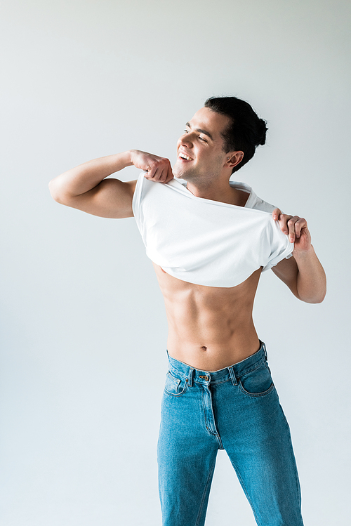 happy man taking off white t-shirt and smiling on white