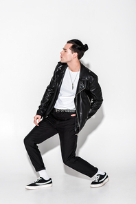 handsome man in black leather jacket posing on white