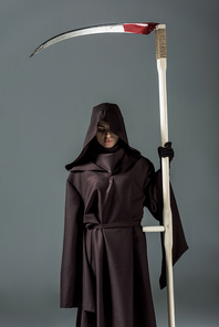 woman in death costume holding scythe on grey