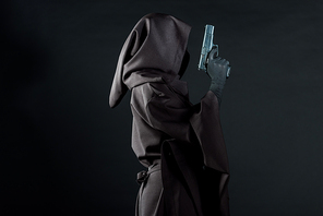 side view of woman in death costume holding gun isolated on black