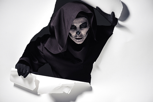 woman in death costume getting out of hole in paper
