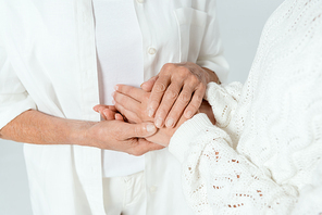cropped view of mother and daughter holding hands isolated on grey