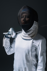 Fencer in fencing mask  and holding rapier isolated on black