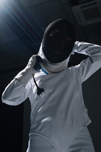 Low angle view of fencer putting on fencing mask
