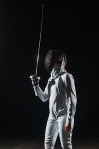 Fencer in fencing mask holding rapier isolated on black