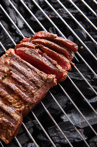 cut fresh grilled tasty steak with rare roasting on grate above black coals