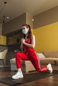 sportive woman in medical mask doing lunges on fitness mat