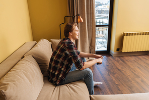 side view of positive man sitting on sofa, end of quarantine concept