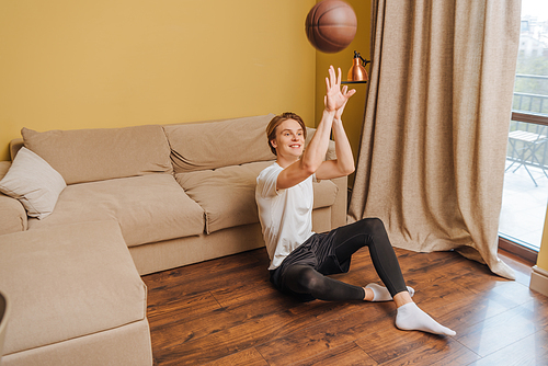 happy man throwing in air football while sitting on floor, end of quarantine concept