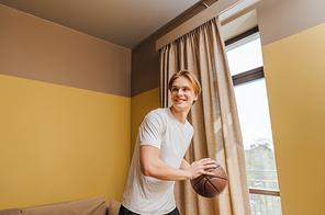 smiling man holding basketball at home, end of quarantine concept