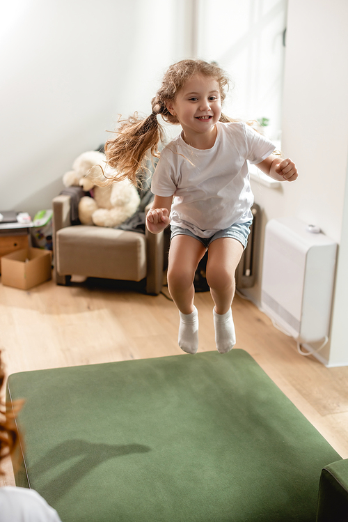 selective focus of cheerful kid jumping on sofa at home