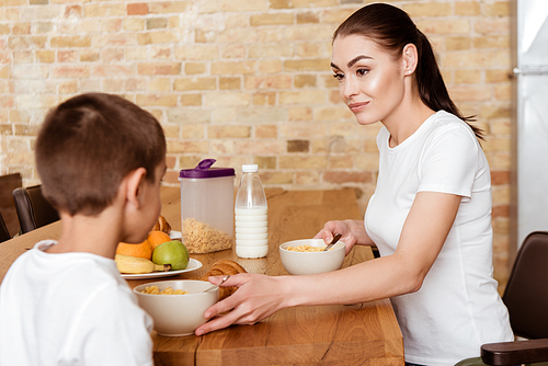 Selective focus of mother looking at son near breakfast on kitchen table