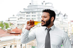 bearded african american man in medical mask drinking beer outside