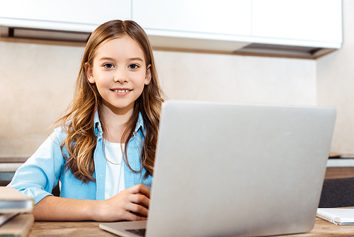 selective focus of happy kid online studying near laptop at home