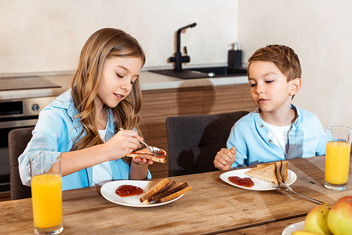 selective focus of kid making toast with jam near brother at home