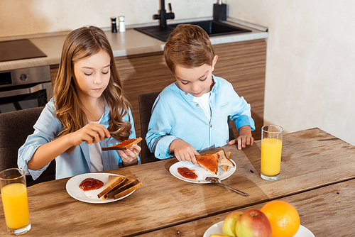 selective focus of kid making toast with jam near cute brother at home