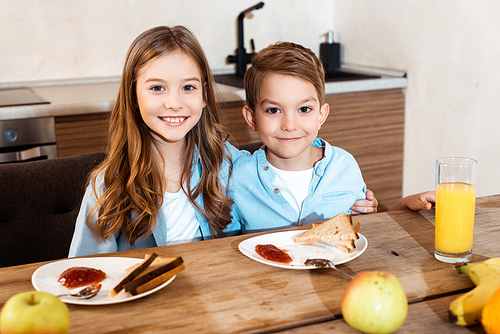 selective focus of happy siblings smiling near tasty breakfast