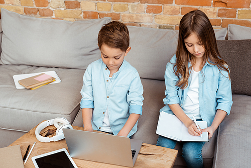 cute siblings online studying near gadgets and headphones at home