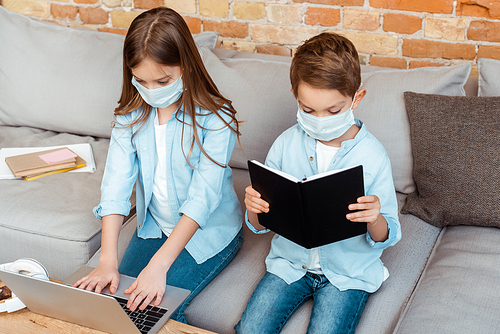 siblings in medical masks e-learning in living room