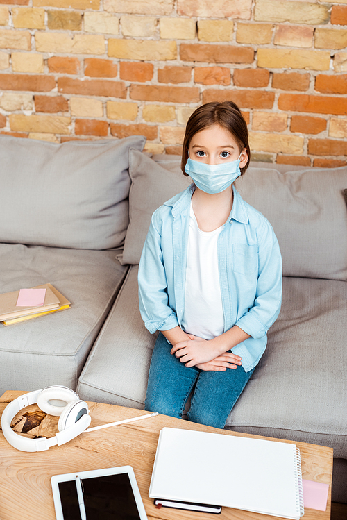 kid in medical mask near digital tablet with blank screen and headphones