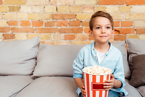 cute boy watching movie and holding popcorn bucket