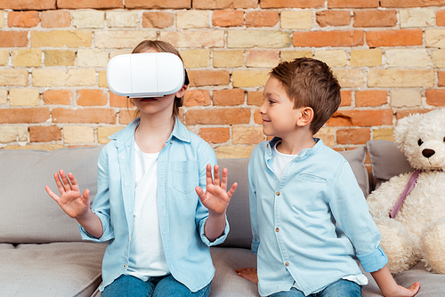 happy brother looking at sister in virtual reality headset