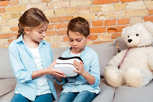 siblings looking at virtual reality headset in living room