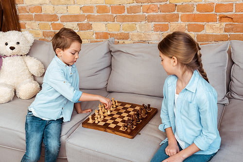 siblings playing chess on sofa in living room