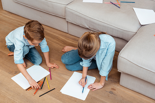 sister and brother sitting on floor and drawing in living room