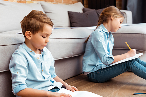 selective focus of cute siblings drawing in living room